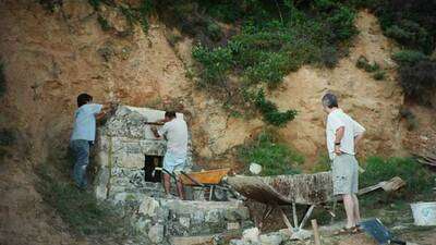 Los dos Ignacios trabajando, y Juan Carlos, el encargado, mirando como restauran la fuente de Covalonso.